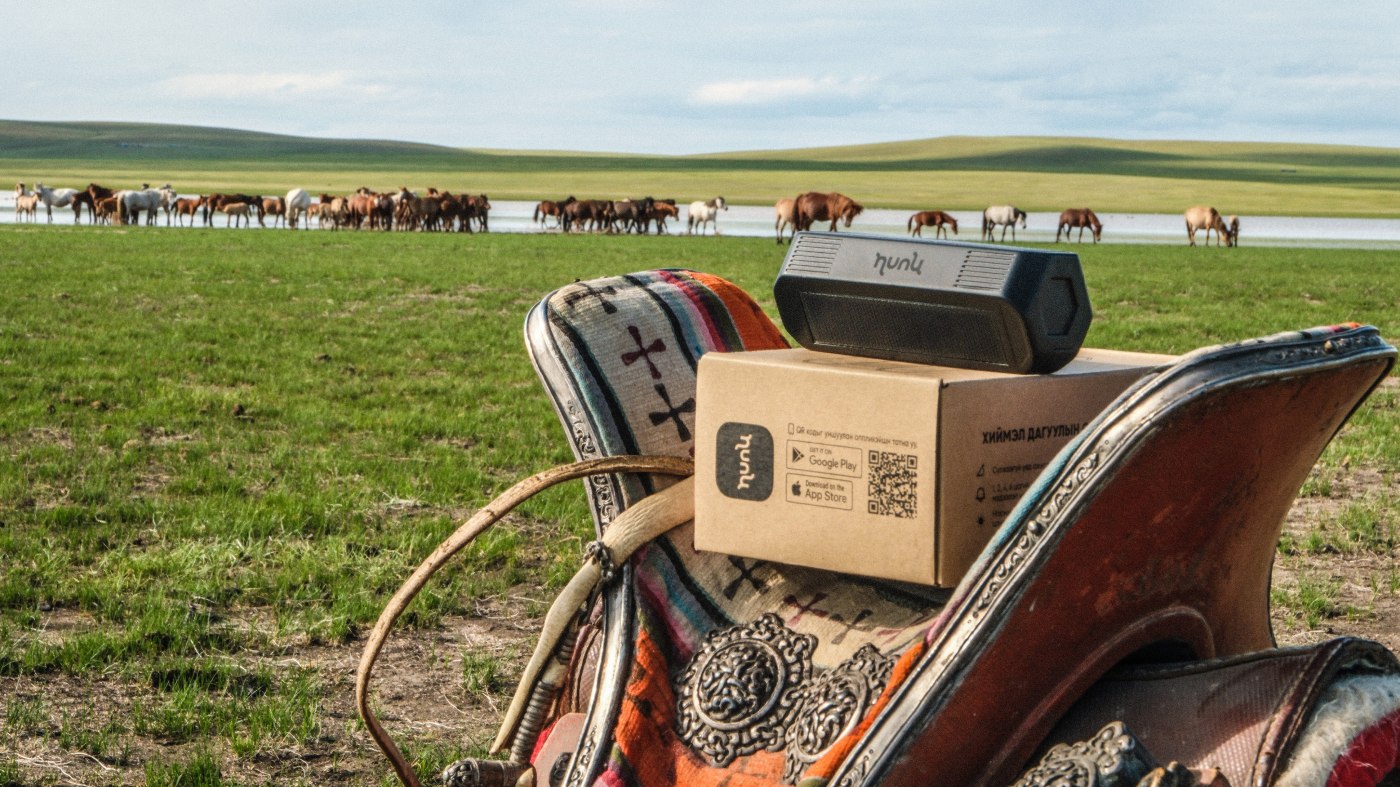 Hunu GPS tracker on a saddle by a herd of horses